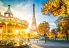 Eiffeltårnet bak en lysende karusell, med høsttrær og morgenlys i Paris.