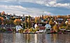 Levanger med trehus, høstfarger og vannspeiling langs kysten i solskinn.