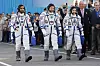 Tre astronauter i romdrakter går forbi en folkemengde ved Bajkonur-kosmodromen.