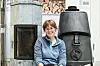 Sofie Sødal Eiksund sitter mellom en vedovn og stablet ved i et NTNU-laboratorium.