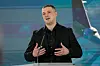 Mykhailo Fedorov taler ved en talerstol foran en fargerik bakgrunn i Kyiv.