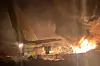 Flammer og røyk fra vrakrester ved et fly om natten.