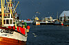 Fiskebåter ved kai på Røst under lofotfisket, med måker over havna.