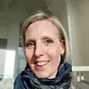 Nærbilde av en kvinne med skjerf i et lyst rom.