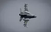 Et ukrainsk F-16-jagerfly sett nedenfra under flyging mot grå himmel.