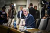 Jonas Gahr Støre sitter ved et bord med mikrofoner under åpen høring på Stortinget, omgitt av presse.