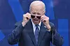 Joe Biden tar av seg solbrillene foran en blå bakgrunn under en seremoni i Chicago.