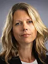Nærportrett av en kvinne med blondt hår mot grå bakgrunn.