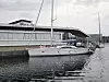 Seilbåt fortøyd ved kai foran en moderne havnebygning.
