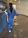 Helsearbeider i blå drakt går med et barn og et intravenøst væskestativ i en korridor.