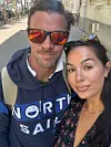 To personer tar selfie på et fortau. Mannen har solbriller og hettegenser med teksten «North Sail».
