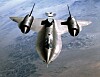 NASA SR-71A Blackbird sett forfra i flukt over landskap, med testutstyr på ryggen.