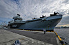 Hangarskipet HMS Prince of Wales ligger ved kai, med en person på kaien foran skipets baug.