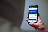 Hånd holder mobiltelefon med nettsiden Slettmeg.no åpen.