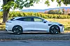 Hvit sedan parkert under et tre ved jorder og høstfargede åser.