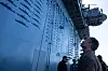 Pete Hegseth ser opp langs den grå skrogsiden på hangarskipet USS Abraham Lincoln.