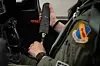 Flyger i grønn uniform kobler Airus-systemet for blæreavlastning i en flycockpit.