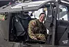 Pilot i kamuflasjeuniform sitter i cockpiten på et AH-64 Apache-helikopter.