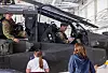 Soldater ved cockpiten på et AH-64 Apache-helikopter i en hangar, med to personer foran helikopteret.