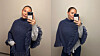Person tar speilselfie i mørk strikkeponcho med smarttelefon.