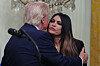 Donald Trump omfavner Kimberly Guilfoyle ved en talerstol i Det hvite hus.