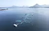 Mowi-oppdrettsanlegg med runde merder i havet ved Aukrasanden og Jendemsfjellet i bakgrunnen.