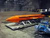 Oransje MOAB-bombe på løfteramme i en stor hangar ved Eglin Air Force Armament Center.