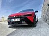 Rød Kia EV6 med skilt 34 BMV 340 parkert ved en steinmur under blå himmel.