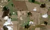 Satellittbilde av åkre og gårdsanlegg, med spredte hvite skyer over landskapet.