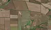 Satellittbilde av rektangulære åkre og jordbruksarealer i ulike grønne og brune nyanser.