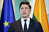 Litauens statsminister Mindaugas Sinkevicius taler ved mikrofoner foran EU-flagg i Berlin.