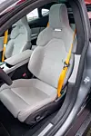 To grå sportsseter med gule sikkerhetsbelter i bil med åpen førerdør. Forsetene fra Recaro er både komfortable og gir god støtte, mens Performance-modellen også har gule belter.