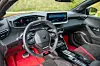 Førerplass i en Cupra med digitalt instrumentpanel, berøringsskjerm, sportsratt og røde setedetaljer.