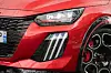 Nærbilde av rød Peugeot-front med LED-lykt, svart grill og felg med rød bremsekaliper.