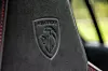 Preget Peugeot-logo på svart skinnsete i bilinteriør.