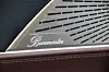 Burmester-høyttaler med perforert metallgitter i bilinteriør med svart og brunt skinn.