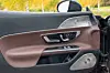 Innside av åpen bildør med brunt skinnpanel, vindusknapper og høyttalergitter.