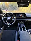 Førerplass i Hyundai N med ratt, digitale skjermer og midtkonsoll, med høstskog utenfor. Fravær av irritasjon er ingen selvfølge i nye elbiler. Vi liker dessuten at betjeningshendlene på rattstammen er kledd i aluminium.