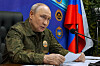 Vladimir Putin i militæruniform ved et bord med dokumenter, russisk flagg og militære emblemer bak.