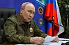 Vladimir Putin i militæruniform ved et bord med dokumenter, russisk flagg og militære emblemer bak.