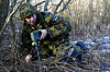 Estisk reservist i kamuflasje plasserer en øvingsmine i kratt ved en vei nær Haapsalu.