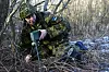Estisk reservist i kamuflasje plasserer en øvingsmine i kratt ved en vei nær Haapsalu.