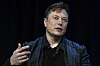 Elon Musk taler med løftet hånd mot mørk bakgrunn under SATELLITE-konferansen.
