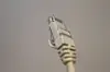 Nærbilde av RJ45-kontakt på en nettverkskabel mot grå bakgrunn.