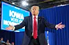 Donald Trump gestikulerer foran et skilt med teksten «Iowa votes» på valgmøte i Iowa.
