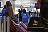 Reisende med rosa koffert ved SAS-innsjekking på Kastrup, med en SAS-ansatt bak skranken.