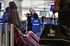 Reisende med rosa koffert ved SAS-innsjekking på Kastrup, med en SAS-ansatt bak skranken.