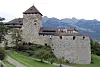 Vaduz slott på en grønn høyde over Vaduz, med fjell i bakgrunnen.