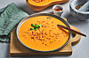 Kremet gresskarsuppe med urter og krydder i en skål på et trebrett.