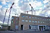Murbygning ved Rikshospitalet i Oslo med byggekraner og skyer på himmelen.